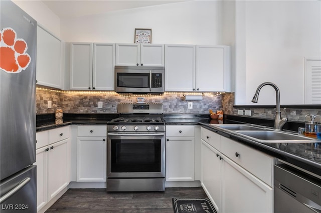 kitchen featuring white cabinets, lofted ceiling, dark wood-type flooring, stainless steel appliances, and sink