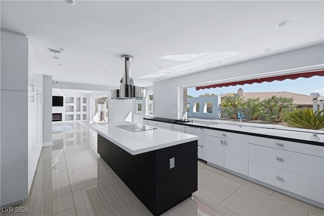 kitchen featuring sink, a fireplace, white cabinetry, a large island, and black electric stovetop