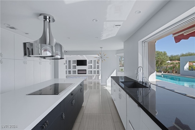 kitchen featuring pendant lighting, black electric cooktop, a notable chandelier, sink, and white cabinetry