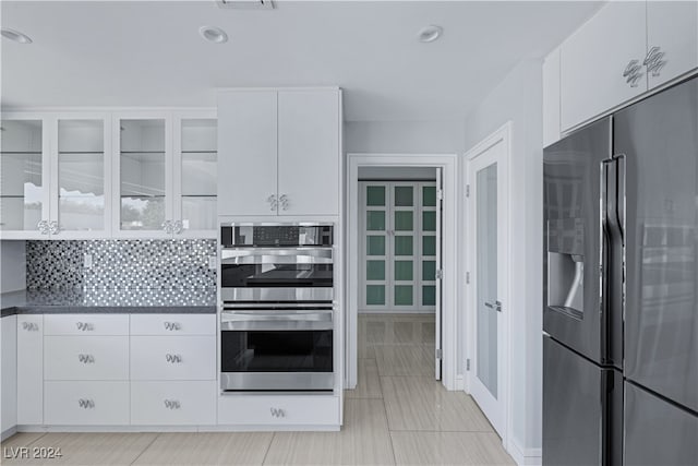 kitchen with appliances with stainless steel finishes, white cabinetry, light tile patterned floors, and tasteful backsplash