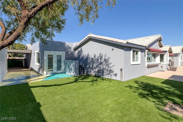 rear view of property with french doors, a patio, and a lawn