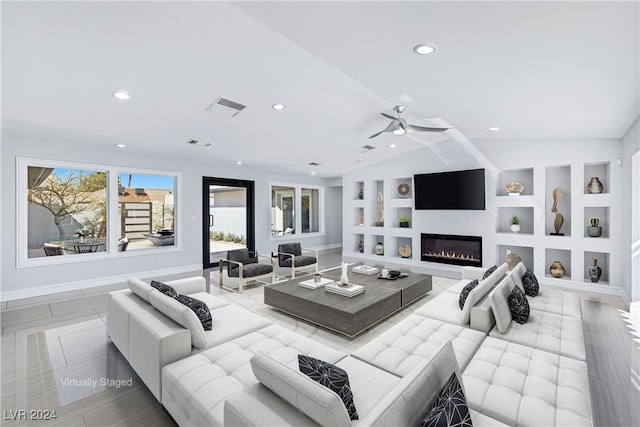 living room with lofted ceiling, built in shelves, light wood-type flooring, and ceiling fan