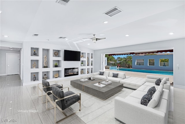 living room with ceiling fan, built in features, and vaulted ceiling