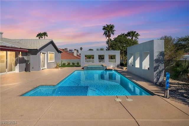 pool at dusk featuring a patio