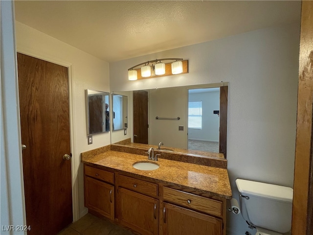 bathroom with a textured ceiling, tile patterned flooring, vanity, and toilet