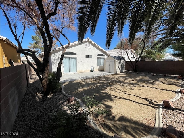 back of house featuring a storage unit and a patio area