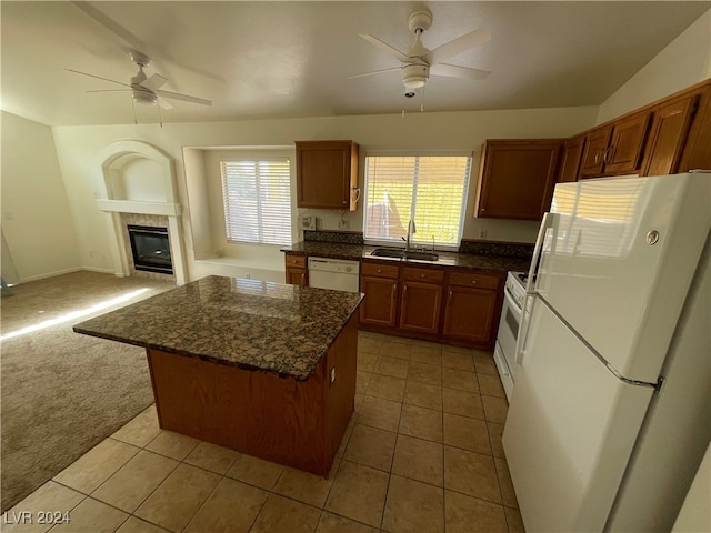 kitchen featuring white appliances, a kitchen island, light carpet, sink, and a fireplace