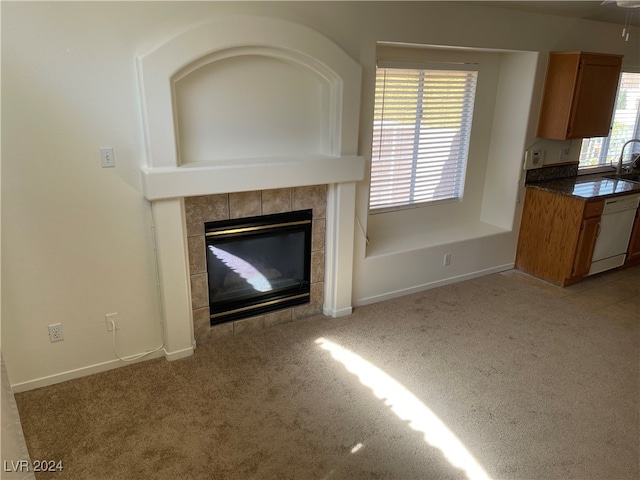 unfurnished living room featuring a healthy amount of sunlight, a tile fireplace, and light colored carpet