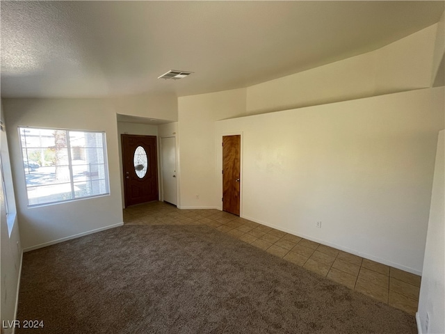 foyer with a textured ceiling, lofted ceiling, and carpet flooring