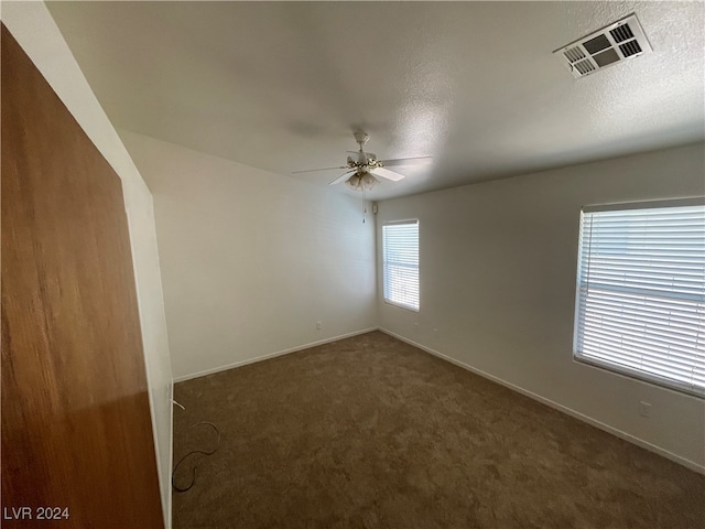 unfurnished room featuring dark carpet, a textured ceiling, and ceiling fan