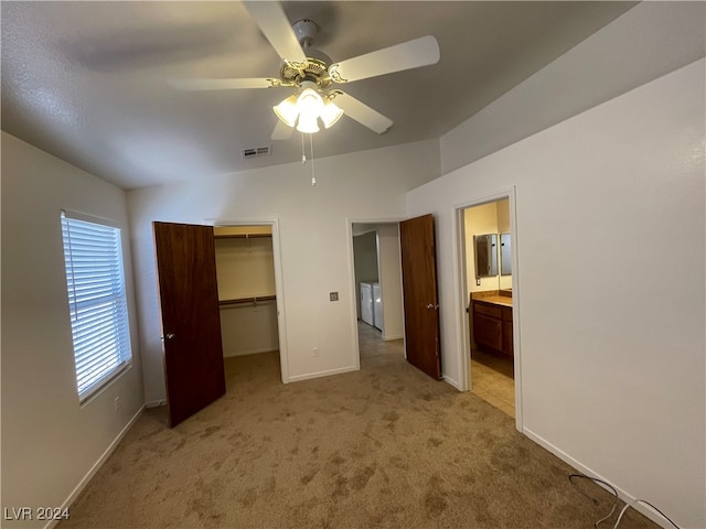 unfurnished bedroom with a walk in closet, ensuite bathroom, ceiling fan, light carpet, and a closet