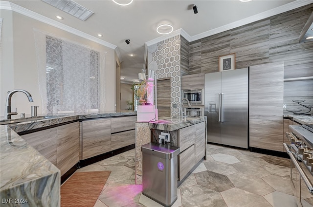 kitchen featuring light stone countertops, tile walls, high end appliances, and crown molding