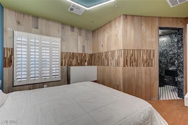 bedroom featuring hardwood / wood-style floors and wooden walls