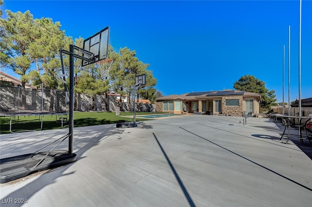 view of basketball court with a trampoline, a swimming pool, and a yard