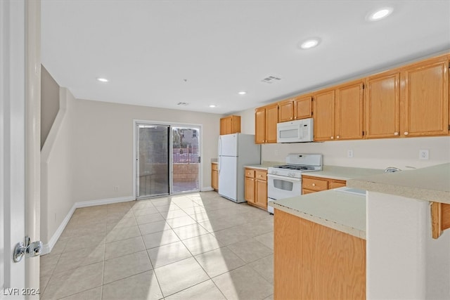 kitchen featuring white appliances, light tile patterned floors, and kitchen peninsula