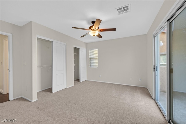 unfurnished bedroom with multiple windows, light colored carpet, ceiling fan, and access to exterior