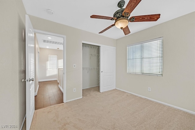 unfurnished bedroom with a closet, light carpet, and ceiling fan