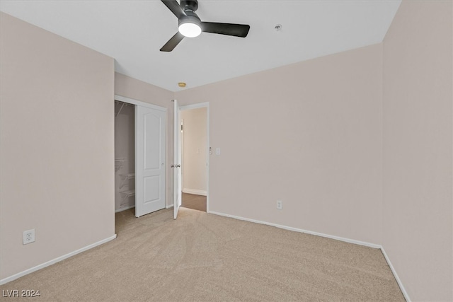 unfurnished bedroom with a closet, light colored carpet, and ceiling fan