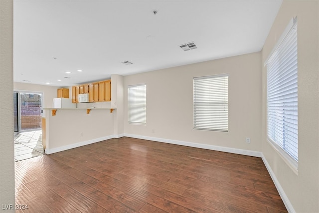 unfurnished living room with a healthy amount of sunlight and dark hardwood / wood-style floors