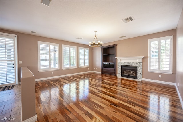 unfurnished living room featuring an inviting chandelier, wood-type flooring, and a fireplace