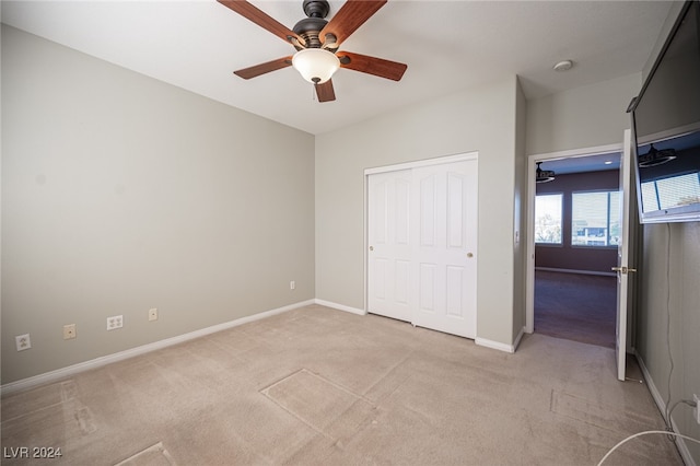 unfurnished bedroom featuring light carpet, a closet, and ceiling fan