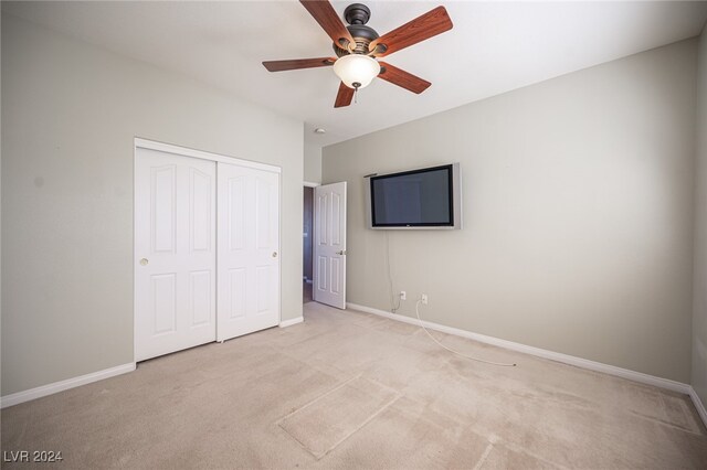 unfurnished bedroom with light colored carpet, a closet, and ceiling fan