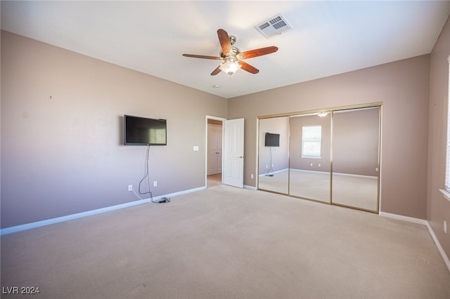 unfurnished bedroom featuring light carpet, a closet, and ceiling fan