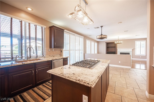 kitchen with sink, backsplash, a center island, decorative light fixtures, and stainless steel dishwasher