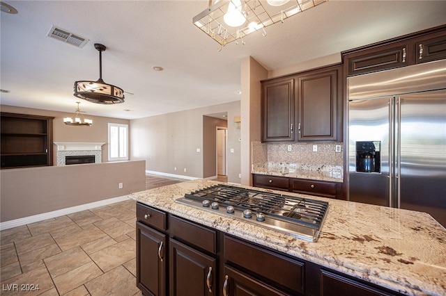 kitchen with appliances with stainless steel finishes, dark brown cabinetry, decorative backsplash, and hanging light fixtures