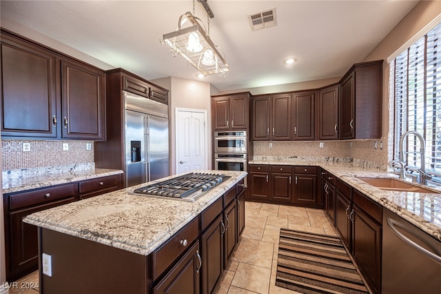 kitchen featuring appliances with stainless steel finishes, a center island, a wealth of natural light, and decorative backsplash