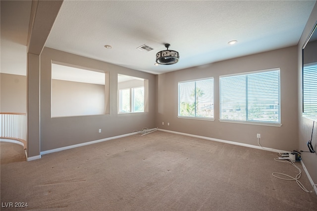 empty room featuring a textured ceiling and light colored carpet