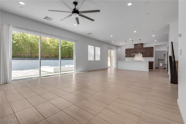 unfurnished living room featuring ceiling fan, plenty of natural light, and light tile patterned floors