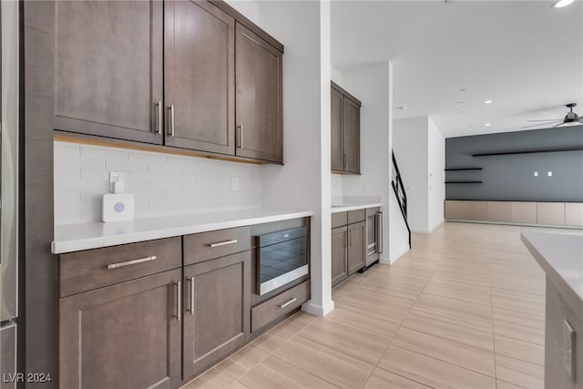 kitchen with dark brown cabinetry, wine cooler, tasteful backsplash, and ceiling fan