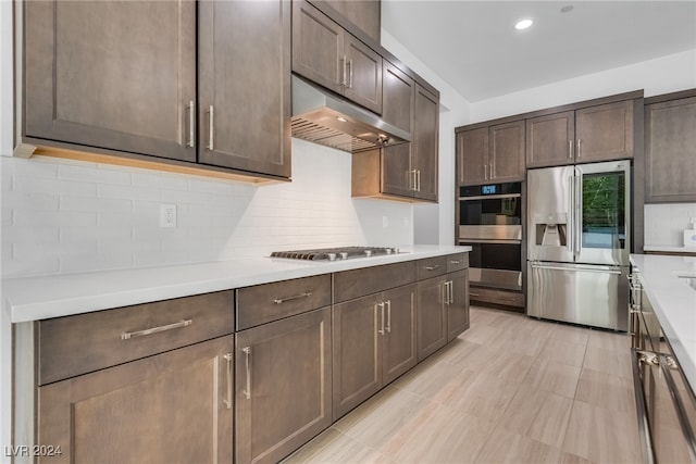 kitchen with appliances with stainless steel finishes, decorative backsplash, and dark brown cabinets