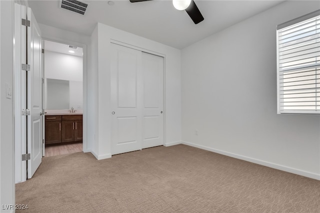 unfurnished bedroom with ceiling fan, light colored carpet, a closet, and sink