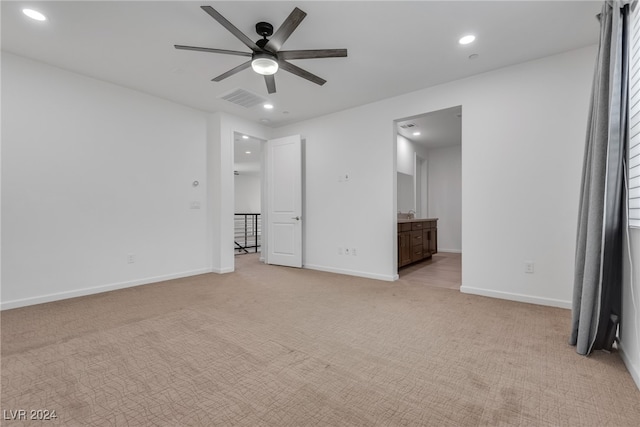 unfurnished bedroom featuring light carpet, ensuite bath, and ceiling fan