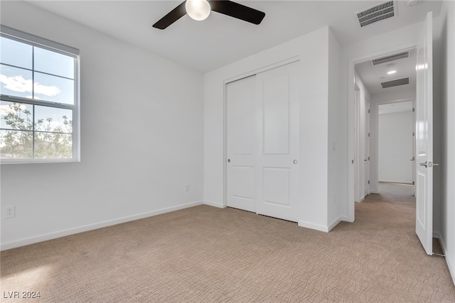 unfurnished bedroom featuring light carpet, a closet, and ceiling fan