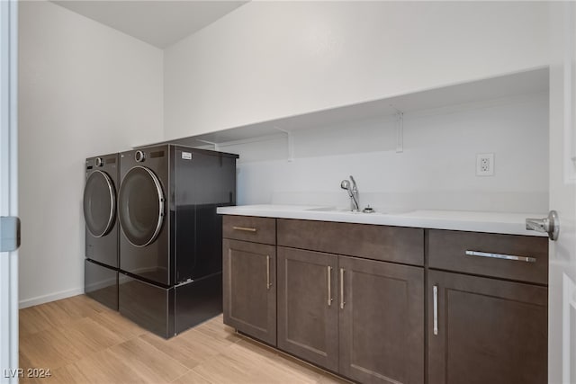 laundry area featuring washing machine and clothes dryer, cabinets, and sink