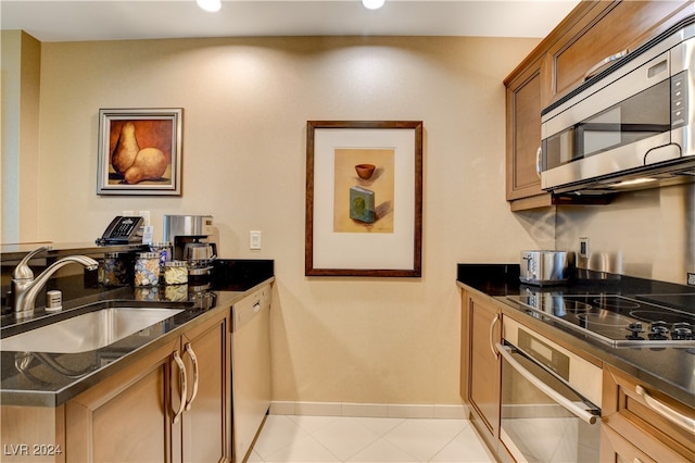 kitchen with stainless steel appliances, sink, and dark stone counters