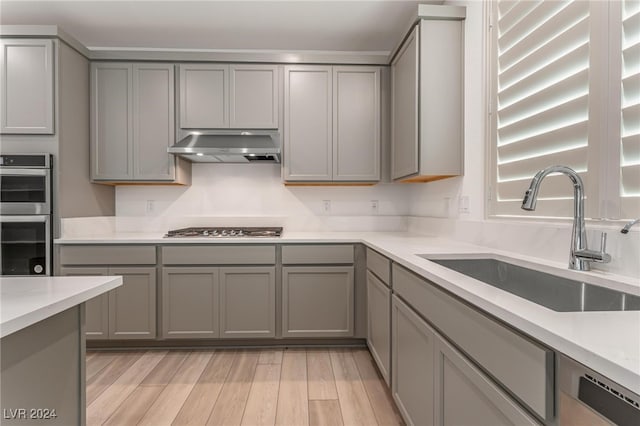 kitchen featuring gray cabinets, light wood-type flooring, sink, and stainless steel appliances