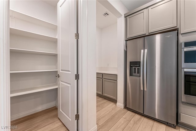 interior space with appliances with stainless steel finishes, gray cabinetry, and light hardwood / wood-style floors