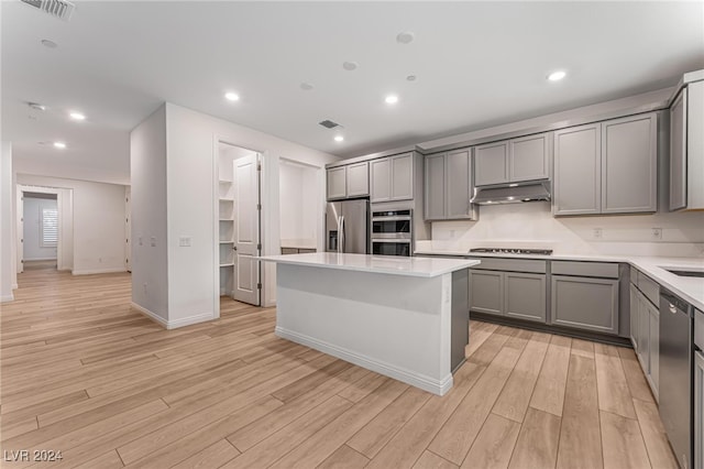 kitchen with light hardwood / wood-style flooring, stainless steel appliances, gray cabinets, and a kitchen island