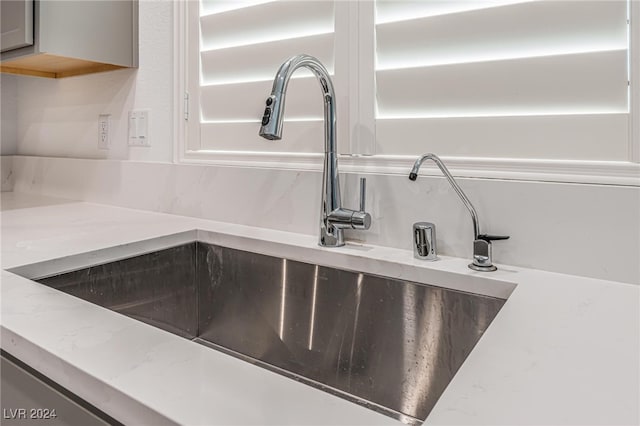 interior details featuring light stone countertops and sink