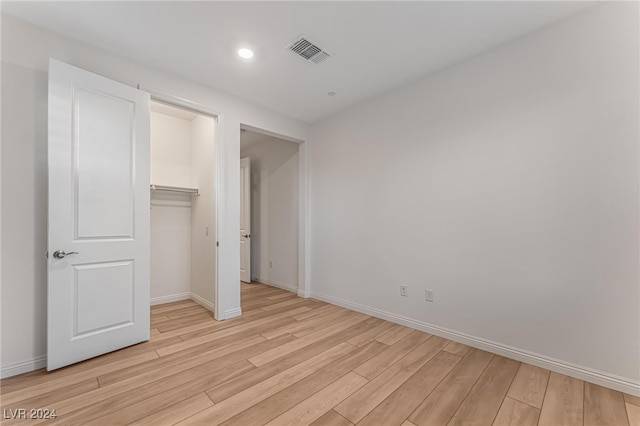 unfurnished bedroom featuring light wood-type flooring, a walk in closet, and a closet