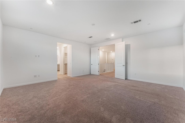 unfurnished bedroom with connected bathroom and light colored carpet