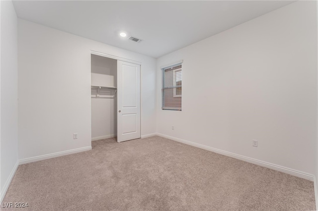 unfurnished bedroom featuring light carpet and a closet