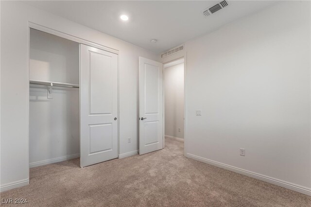 unfurnished bedroom featuring light carpet and a closet