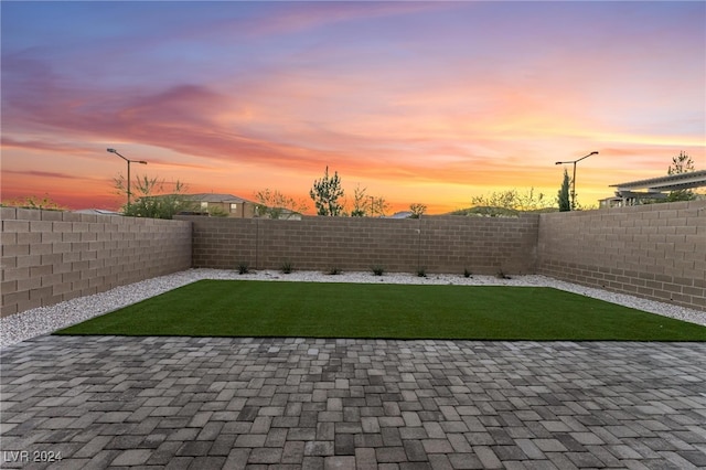 yard at dusk featuring a patio