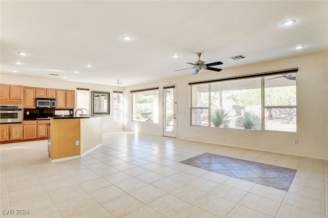 kitchen featuring light tile patterned flooring, stainless steel appliances, ceiling fan, a center island with sink, and sink