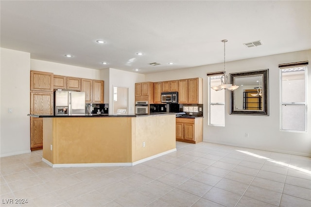 kitchen with appliances with stainless steel finishes, hanging light fixtures, backsplash, light tile patterned floors, and a center island